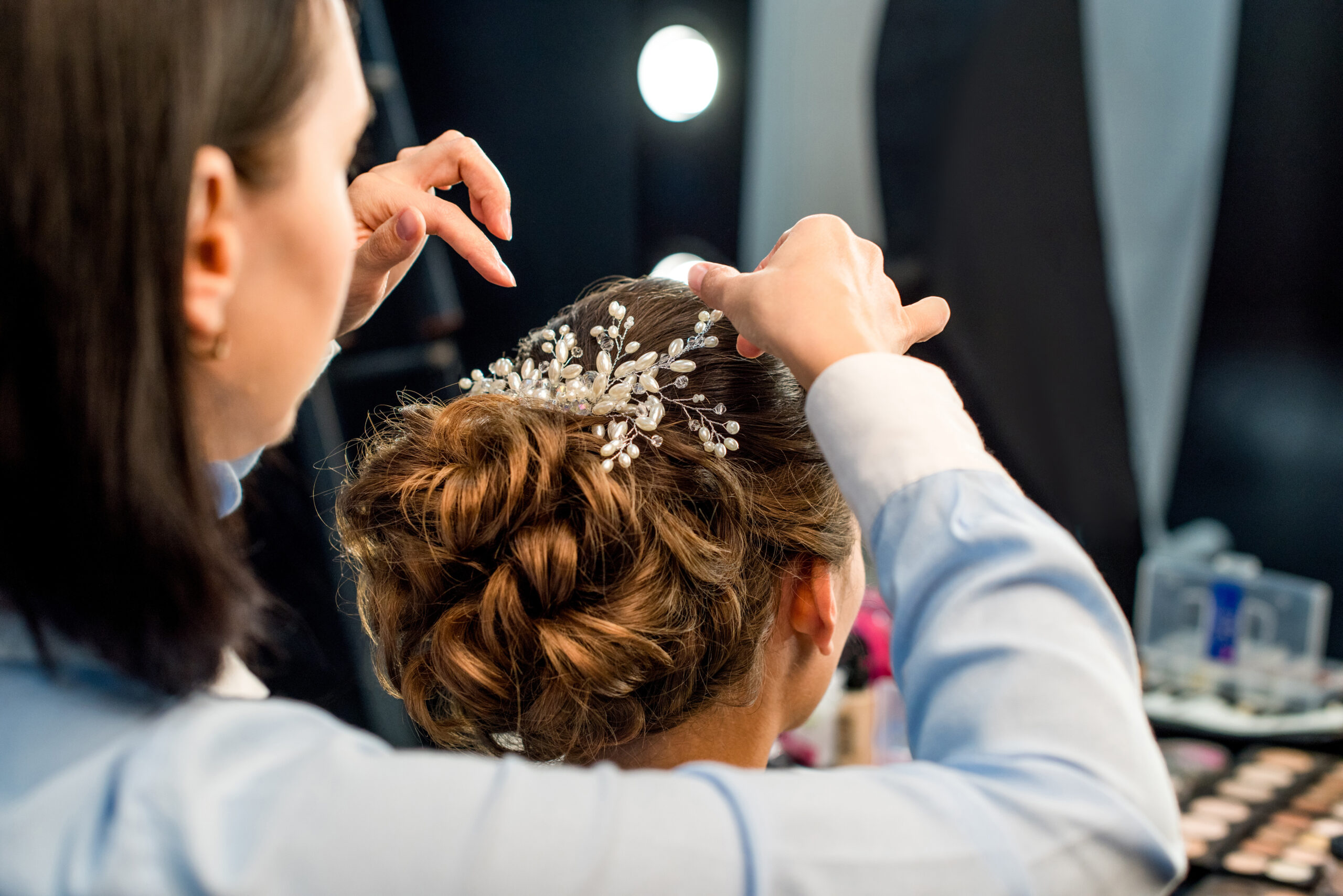partial view of hairstylist decorating clients hairstyle with beautiful accessory